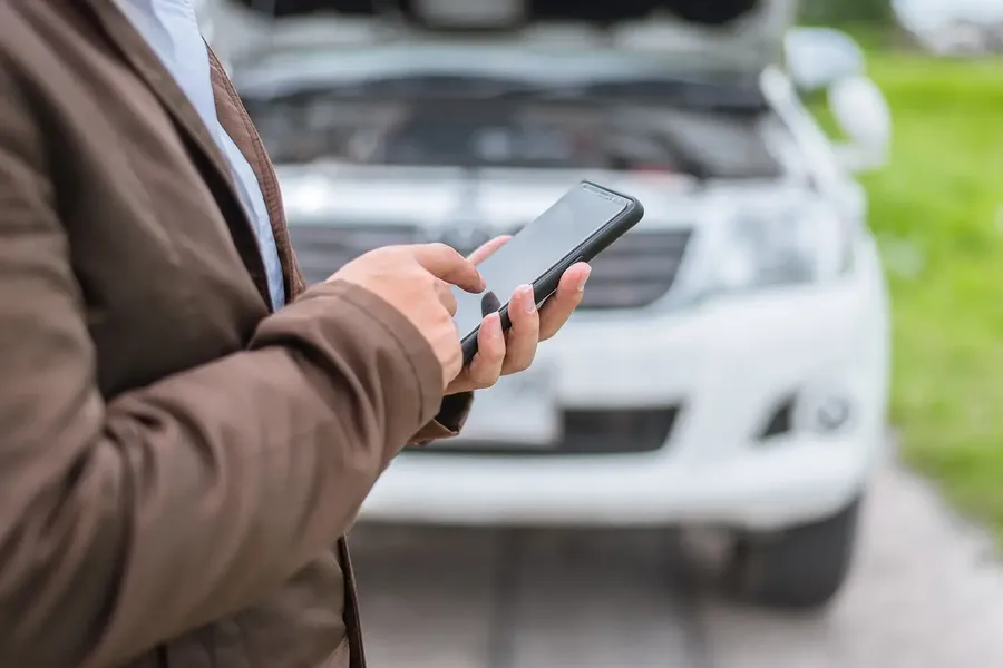 Driver calling for roadside help beside a car