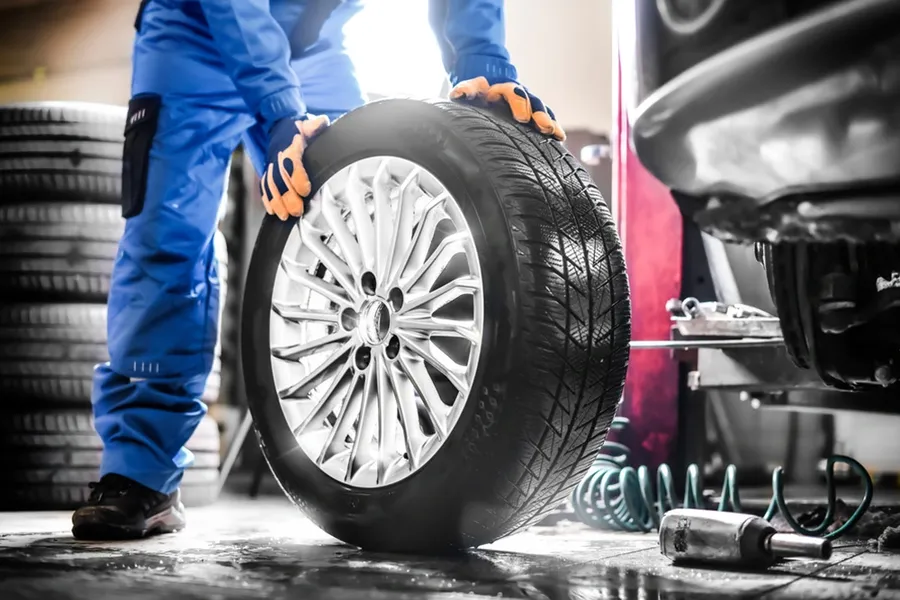 Mechanic carrying a new tire and wheel